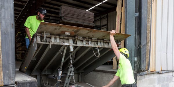 Technicians performing maintenance on dock leveler