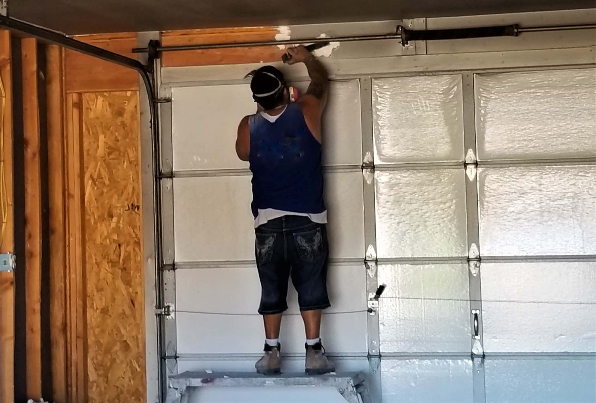 construction worker installing a roll up garage door in a garage t20 ywmgpw