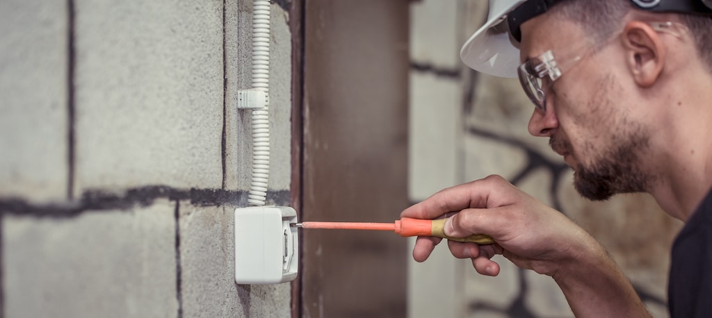 male electrician technician, connects the equipment with a tool